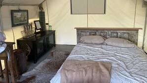 A tented room with a bed, a desk, and a framed picture on the wall. - Glamping Tent on the Evans Farm near Joseph, Oregon. (joseph)