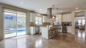 A spacious kitchen with a central island, bar stools, and a view of a swimming pool. - Cardiff 5 bedroom home w/pool &  gated driveway near beach (Encinitas)