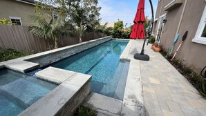 A swimming pool with stone steps and a red umbrella. - Cardiff 5 bedroom home w/pool &  gated driveway near beach (Encinitas)