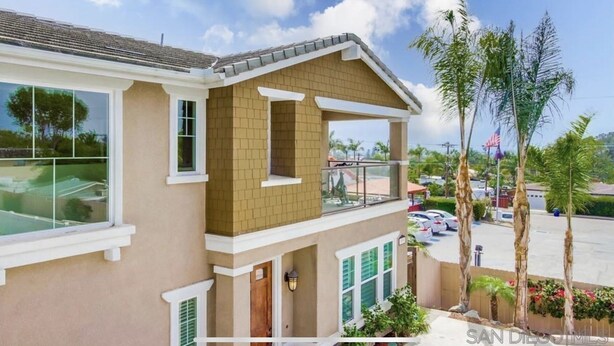A two-story house with a balcony, large windows, and a view of a parking area with palm trees. - Cardiff 5 bedroom home w/pool &  gated driveway near beach (Encinitas)