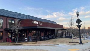 A brick building with a sign reading "1885 Grill" and outdoor seating. - Blue Bungalow-Downtown Acworth (Acworth)