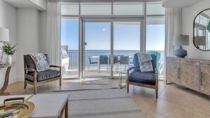 En rymlig balkong med fri utsikt över havet, inredd med två stolar och ett bord.