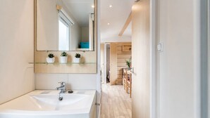 Et moderne badeværelse med en stor vask, et spejl og en glashylde med plantekasser.