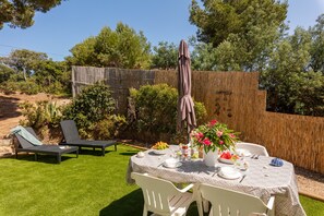Eine Terrasse mit Esstisch, umgeben von Grünpflanzen und einem Holzzaun.