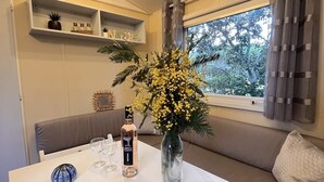 Un rincón acogedor con una mesa dispuesta para dos, un jarrón con flores amarillas y una botella de vino.