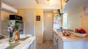 Cocina compacta con microondas, estufa y un tazón de verduras en la encimera.