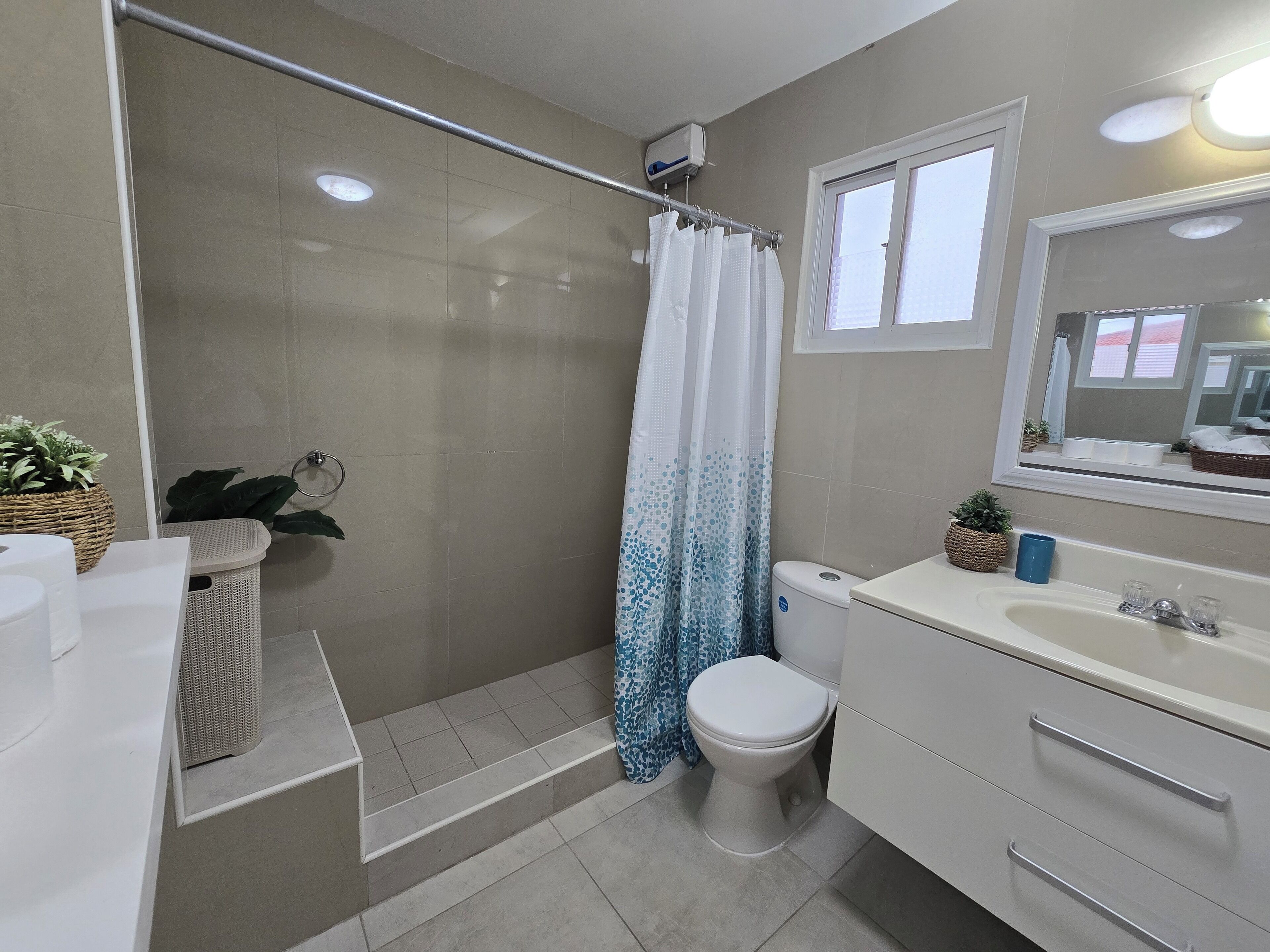 Een badkamer met een douche, toilet, wastafel en een spiegel.