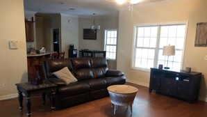 A living room with a leather sofa, a coffee table, and a dining area in the background.