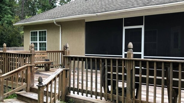A house with a covered patio, wooden deck, and a screened porch.