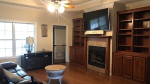A living room with a fireplace, television, and wooden bookshelves.
