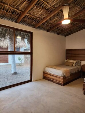 A room with a bed, a window, and a thatched ceiling.