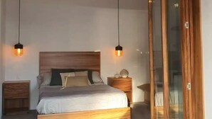 A bedroom with a wooden bed, two bedside tables, a ceiling fan, and a sliding glass door.