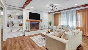Una sala de estar con chimenea, televisor, sofá y estantería.