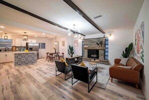 A spacious living area with a kitchen, dining area, and a fireplace. - Modern Chic Living 4BRs Home with hot tub  - Prime Location (Houston)