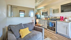 A modern kitchen with stainless steel appliances, a grey sofa with a yellow throw, and a large mirror on the wall. - Lakeside Hideaway Cabin - Rest & Recharge (Willis)
