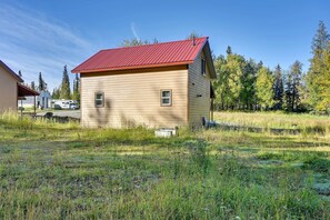 A single-story building with a red roof, surrounded by grass and trees. - Soldotna Vacation Rental ~ 8 Mi to Kenai River! (Soldotna)