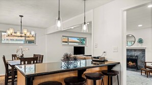 A modern kitchen with a central island, bar stools, pendant lighting, and a fireplace. - Spectacular Mountain Views - Hot Tub & Fire Pit (Centennial)