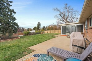 A backyard with a patio, a covered grill, a pool table, and a covered seating area.