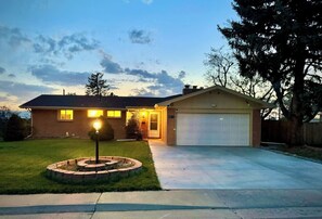 A two-story house with a garage, a well-maintained lawn, and a circular stone feature.
