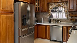 Une cuisine avec des meubles en bois, des appareils électroménagers en acier inoxydable et un sol carrelé.