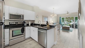 A modern kitchen with stainless steel appliances, white cabinetry, and a central island with a sink and knife block. - Villa 5028 on Duck Key Boat Slip Available - 2BD 2.5BA (Duck Key)