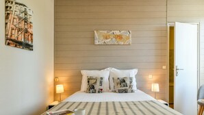 A hotel room with a bed, two bedside lamps, a magazine, and a cup on the bed. - Logis Hostellerie du Neez (Gan)