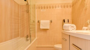 A bathroom with a glass-enclosed shower, a toilet, and a sink with a towel rack. - Logis Hostellerie du Neez (Gan)