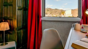 A room with a window, a chair, a table with a teapot and cup, and a lamp. - Logis Hostellerie du Neez (Gan)