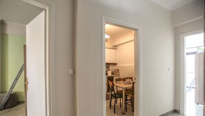 Corredor que dá para uma sala de jantar, com mesa e cadeiras.