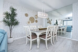 A dining area with a white table and chairs, a hanging light fixture, and decorative wall art.
