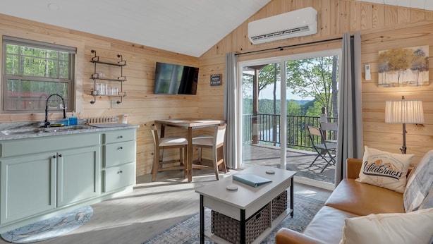A cozy cabin interior with a kitchen, dining area, and a balcony with a view. - Lake View Nature Cabin at Bear Bluff Retreat (Walling)