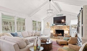 A spacious living room with a high ceiling, a fireplace, and a large TV. - Lakefront with 2-Tier Dock & Jet Ski Dock, Boat Lift, Pool Table, Kayaks, Tubes (Dawsonville)
