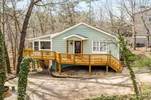 Stroll up to the charming single-story house with a wooden deck and enjoy the serene wooded surroundings.