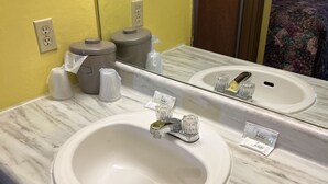 A bathroom with a marble sink, yellow walls, a mirror, and toiletries. - Lebanon Inn Motel (Lebanon)