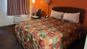 A hotel room with a large bed, a chair, a desk, a lamp, and a painting on the wall. - Lebanon Inn Motel (Lebanon)