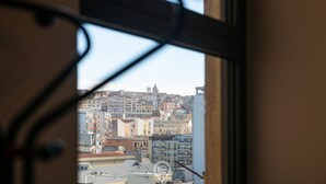 A view through a window with a metal frame, overlooking a densely packed urban area with various buildings and a dome structure in the distance. - Harbor View Apartment (Cagliari)
