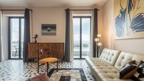 A modern living room with a sofa, a wooden cabinet, a chair, and a patterned rug. - Harbor View Apartment (Cagliari)