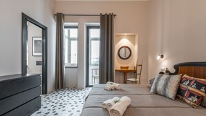 A hotel room with a bed, a desk, a chair, and a mirror. - Harbor View Apartment (Cagliari)