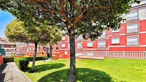 Une cour avec un arbre, un bâtiment rouge doté de balcons et un chemin pavé.