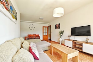 Ein Wohnzimmer mit einer Couch, einem Holztisch, einem Fernseher und einer Uhr an der Wand.