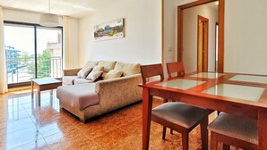 Un salon comprenant un canapé, une table à manger avec un plateau en verre et une chaise.