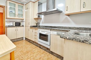 A kitchen with granite countertops, a microwave, oven, and stainless steel sink.