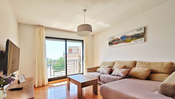 A modern living room with a sofa, a coffee table, a TV, and a large window with a view of buildings. - Disconnectaengalicia La Perla Premium, swimming pool and parking (Portonovo)