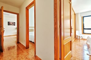 Ein Hotelzimmer mit Bett, Holzschrank, weißem Stuhl und Fenster.