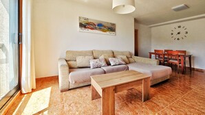 A living room with a sofa, a wooden table, a dining set, a clock, and a painting on the wall. - Disconnectaengalicia La Perla Premium, swimming pool and parking (Portonovo)