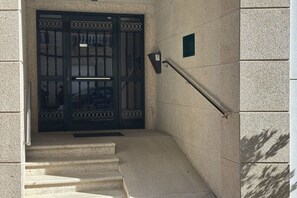 A building entrance with a double door, a handrail, and a small plaque on the wall.