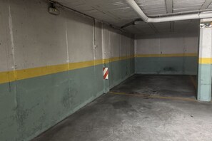 Autotalli, jonka seinät ovat betonia, siinä on keltainen viiva ja punavalkoinen kyltti.