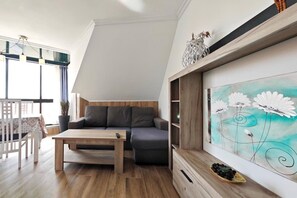 A modern living room with a wooden coffee table, a gray sofa, and a painting of flowers.