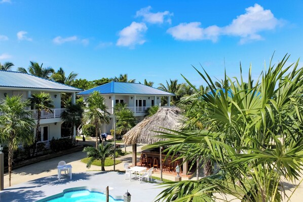 A resort with a pool, outdoor seating, and a thatched-roof structure.