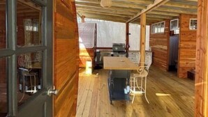 A wooden cabin interior with a dining area, a door with glass panels, and a ceiling with exposed beams. - Family & Pet Friendly Treehouse with Amazing Views (Wildwood)